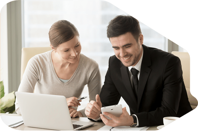 A man and a woman smiling while looking at a laptop